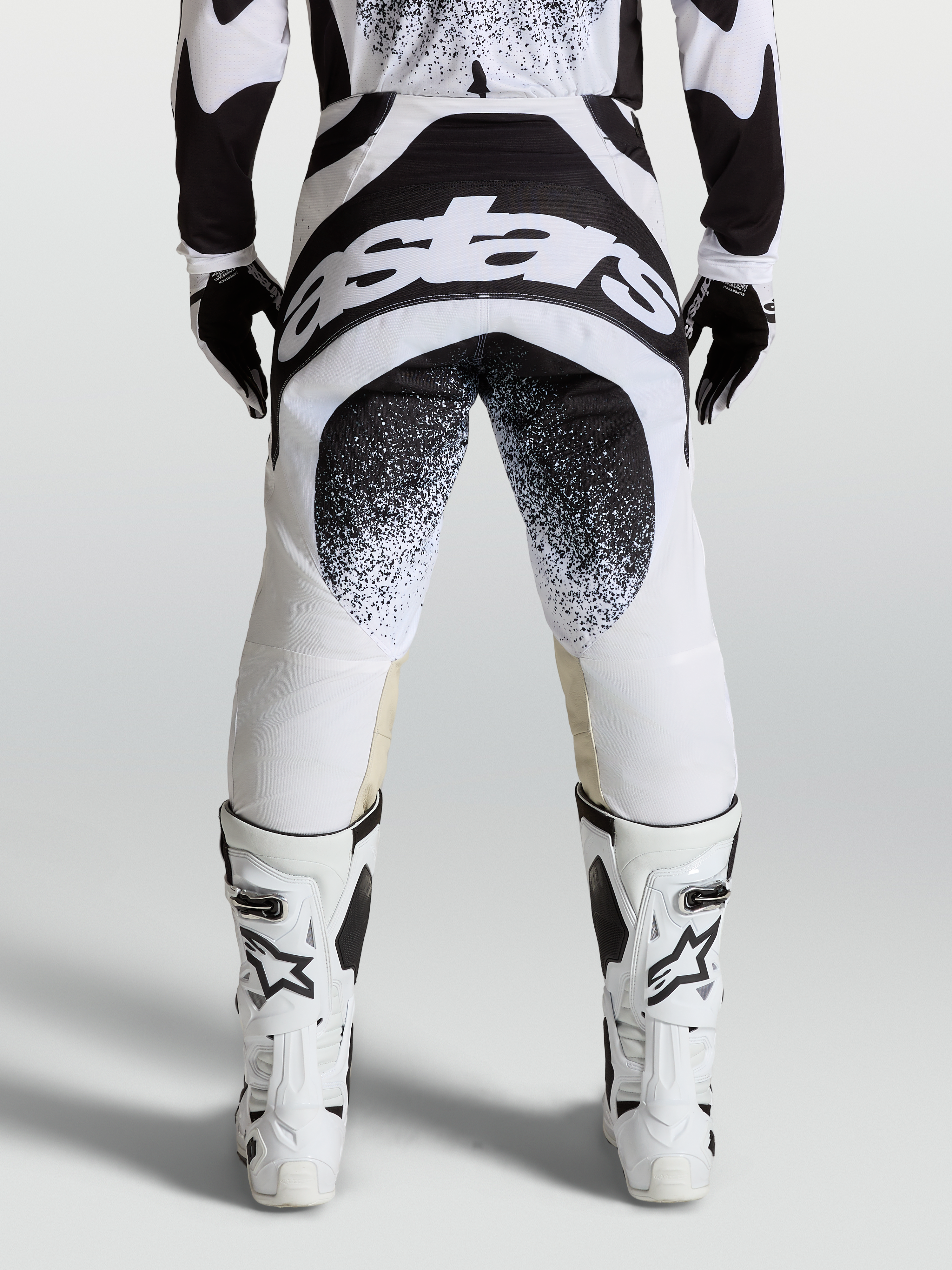 Alpinestars Techstar Swan Bukser, professionelle motocrossbukser i sort og hvid, set bagfra med logo-grafik og Babel knækonstruktion.