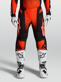 Alpinestars 2027 Techstar Swan motocrossbukser i rød og sort, stylet med hvide crossstøvler og handsker.