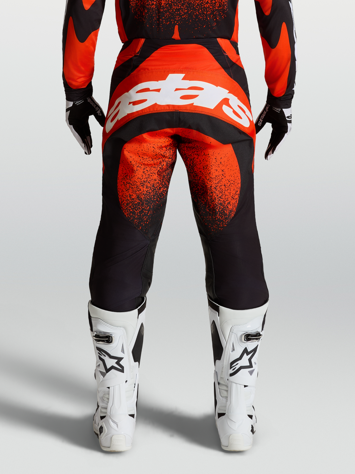 Alpinestars Techstar Swan Pants, Red and Black motocross gear, on-model rear view with white Alpinestars logo and white racing boots.