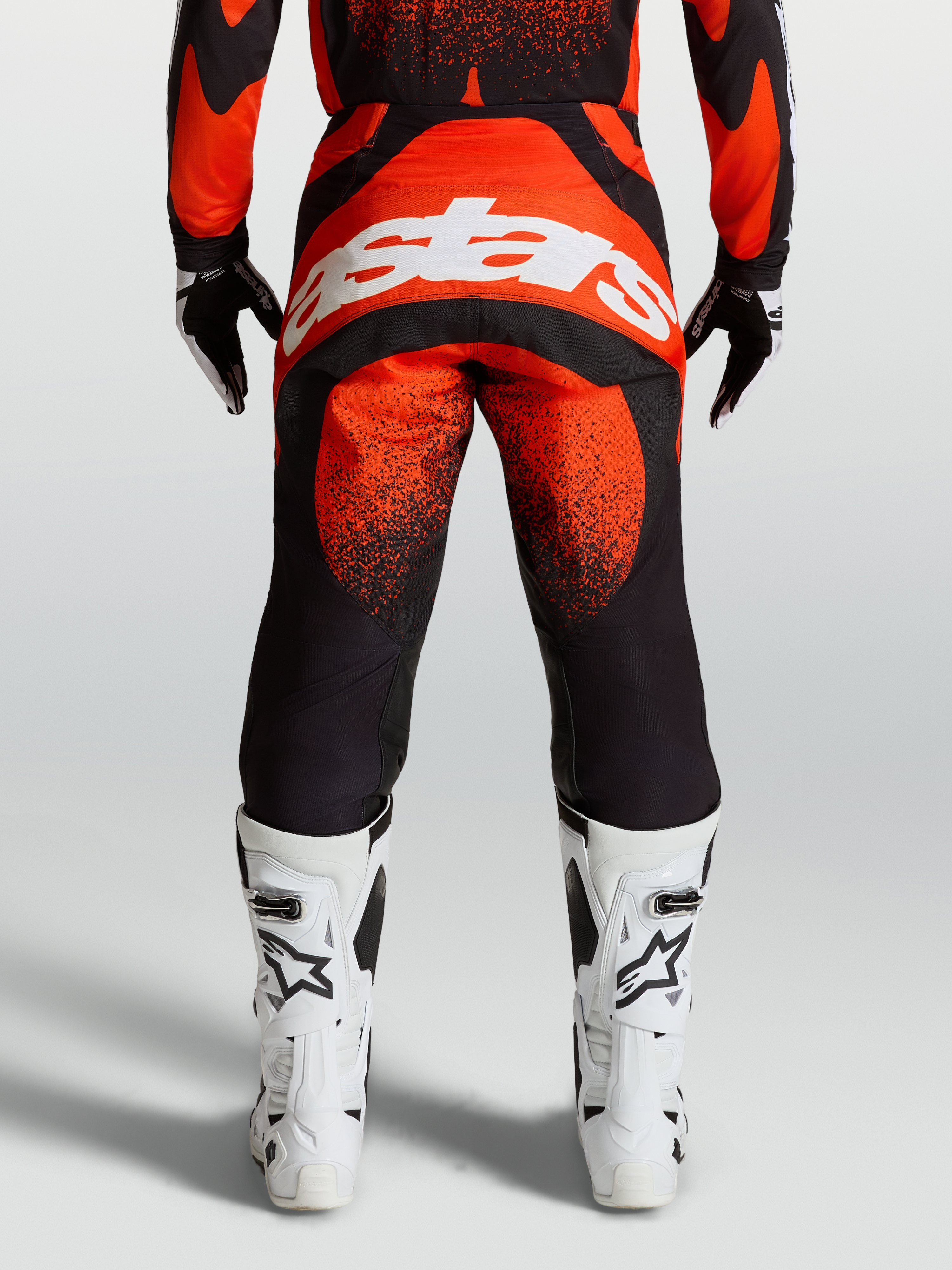Alpinestars Techstar Swan Pants, Red and Black motocross gear, on-model rear view with white Alpinestars logo and white racing boots.