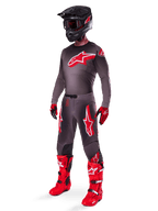 Alpinestars 2025 Supertech Lipan bukser, motocross-bukser, Smoke Bright Red, mørkegrå base med store røde Alpinestars-logoer på lårene, båret med matchende trøje, sort hjelm, rød-sorte handsker og klare røde støvler, koordineret motocross-outfit på professionelt niveau