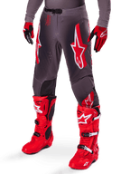 Alpinestars 2025 Supertech Lipan-udstyrssæt, grå motocrossbukser med markante røde og hvide stjernelogoer, kombineret med klare røde performancestøvler og røde og sorte handsker, designet til racing på professionelt niveau