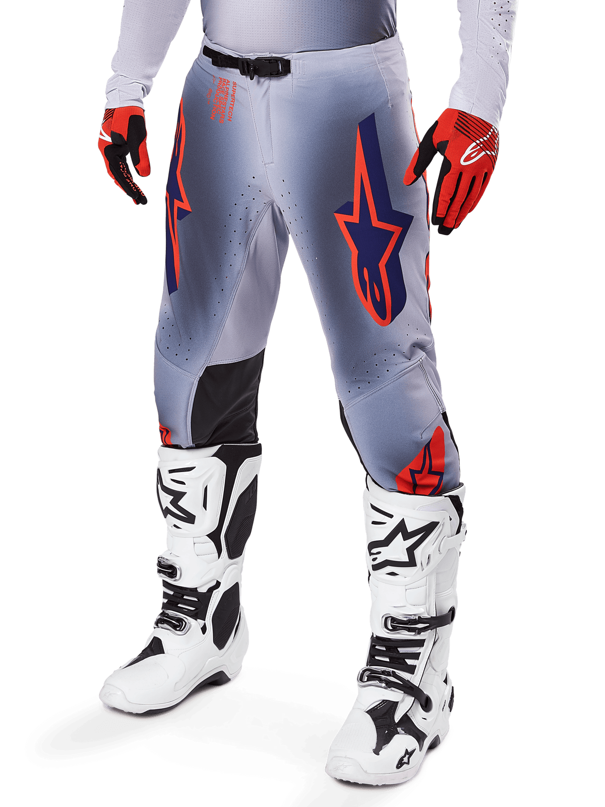 Alpinestars 2025 Supertech Lipan bukser, motocross-bukser, grå og orange fluo, med mørkeblå stjernedesigns og sorte indvendige knæpaneler, båret med rød-orange handsker og hvide støvler, professionelt udstyr til terrænkørsel