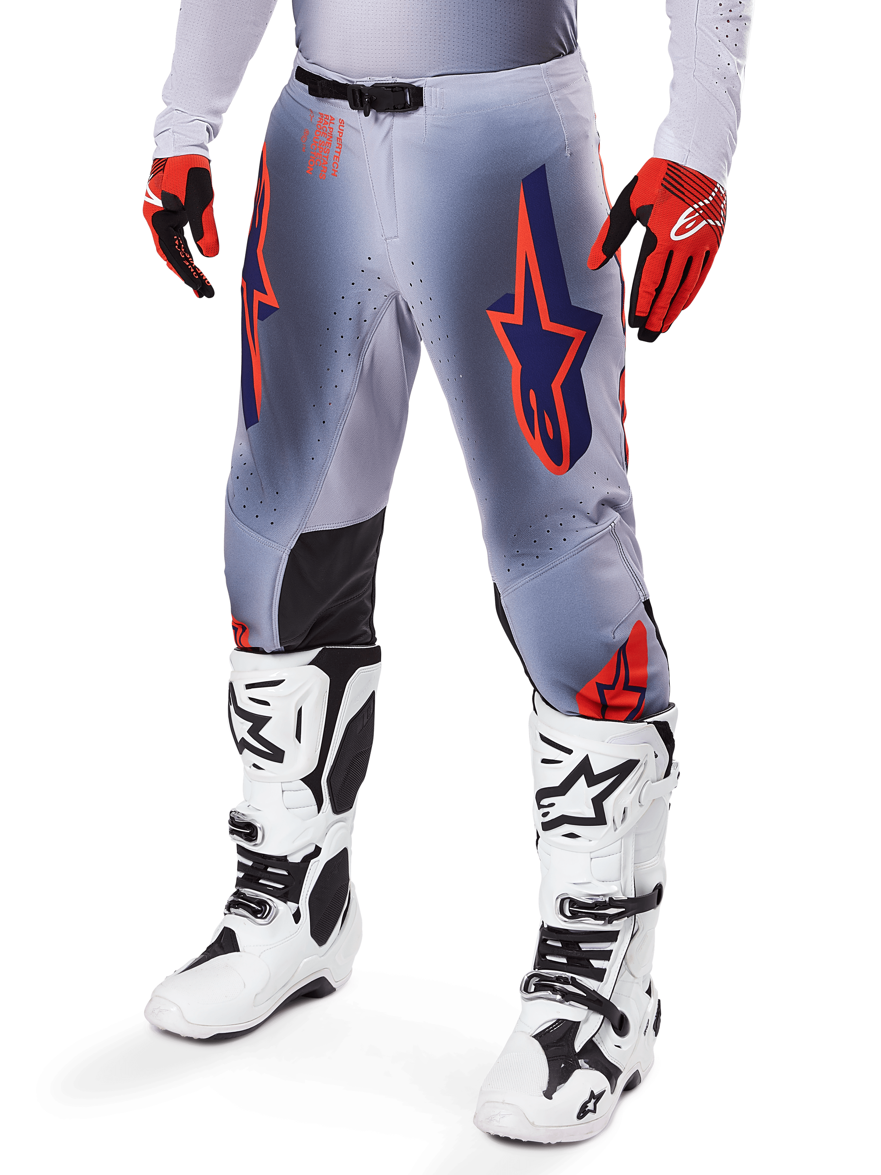 Alpinestars 2025 Supertech Lipan bukser, motocross-bukser, grå og orange fluo, med mørkeblå stjernedesigns og sorte indvendige knæpaneler, båret med rød-orange handsker og hvide støvler, professionelt udstyr til terrænkørsel