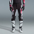 Alpinestars 2026 Supertech AFD Vista Gear Set, motocrosskører iført sorte bukser med store hvide og røde logoer, matchende performance jersey med bordeauxrøde manchetter, sorte handsker og hvide professionelle racingstøvler, højtydende off-road racingoutfit