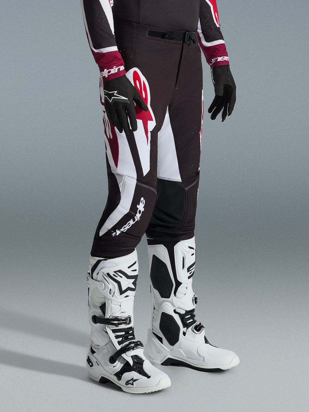 Alpinestars 2026 Supertech AFD Vista bukser, motocross-bukser, sort, rød og hvid, med markante grafiske mønstre og branding, båret med hvide og sorte off-road støvler og sorte handsker, professionel atletisk pasform.