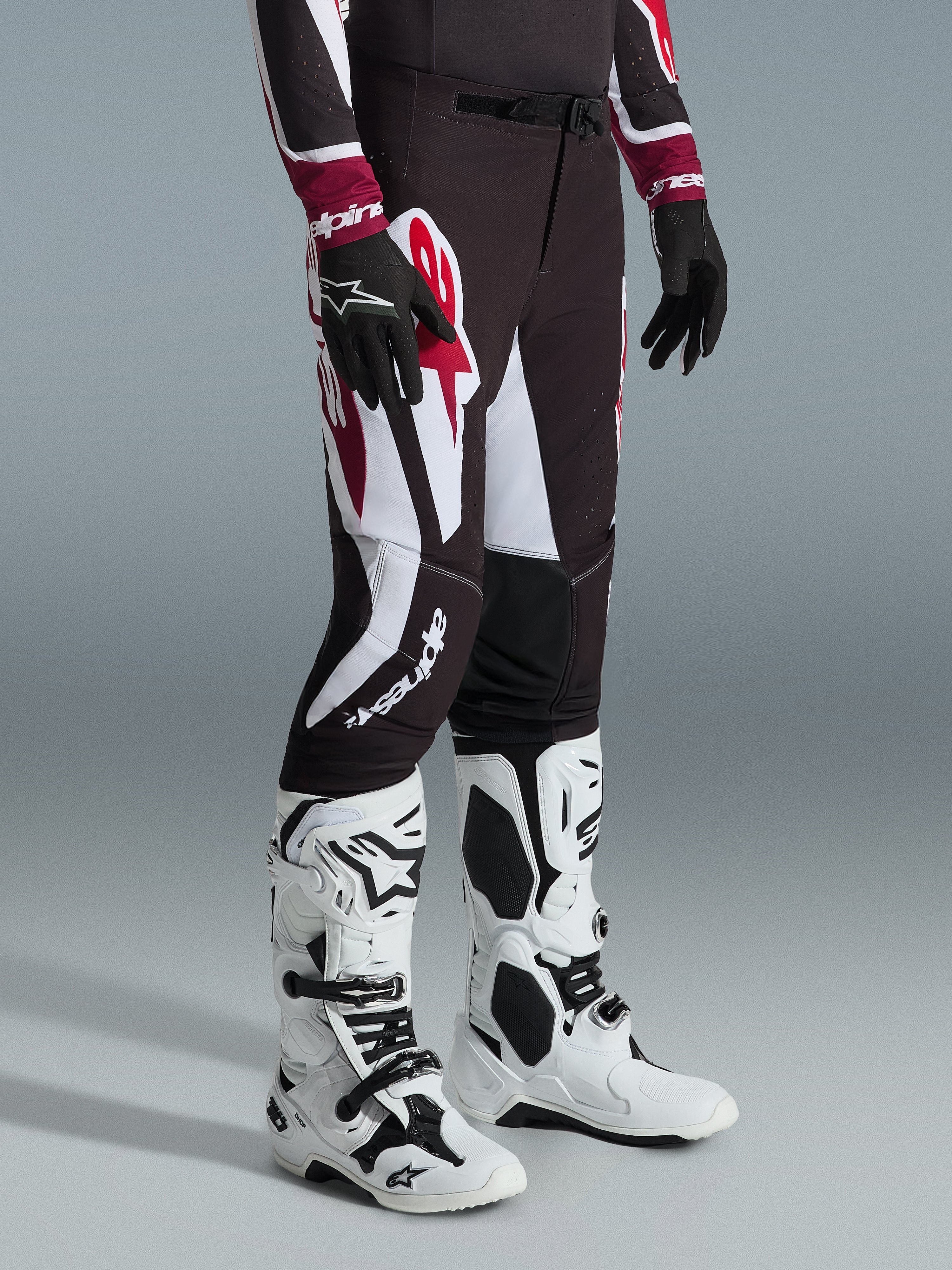 Alpinestars 2026 Supertech AFD Vista bukser, motocross-bukser, sort, rød og hvid, med markante grafiske mønstre og branding, båret med hvide og sorte off-road støvler og sorte handsker, professionel atletisk pasform.