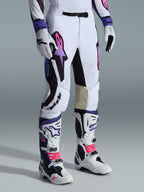 Alpinestars 2026 Supertech AFD Vista bukser, motocross-bukser, hvid, lilla og sort, med et lyserødt og lilla gradient Astar-logo, båret med matchende hvide og lilla motocross-støvler og -handsker, atletisk race-pasform med indvendige knæpaneler i lyst læder og perforerede detaljer.