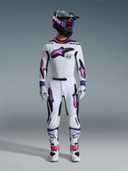 Motocrosskører iført et komplet racersæt, Alpinestars 2026 Supertech AFD Vista bukser og trøje i hvid, lilla og sort, matchende handsker, hvide og sorte støvler, sort hjelm med lilla goggles, slank atletisk pasform til terrænkørsel
