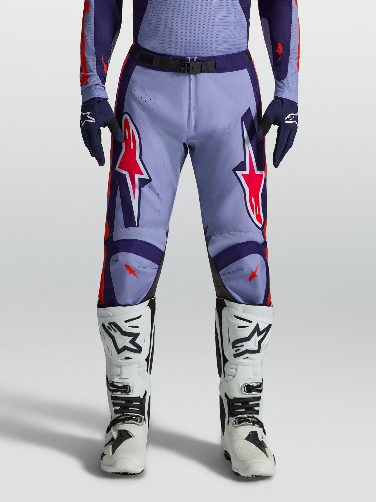 Alpinestars Racer Air Hunt motocrossbukser i lilla med pink detaljer, båret med hvide motorcykelstøvler.