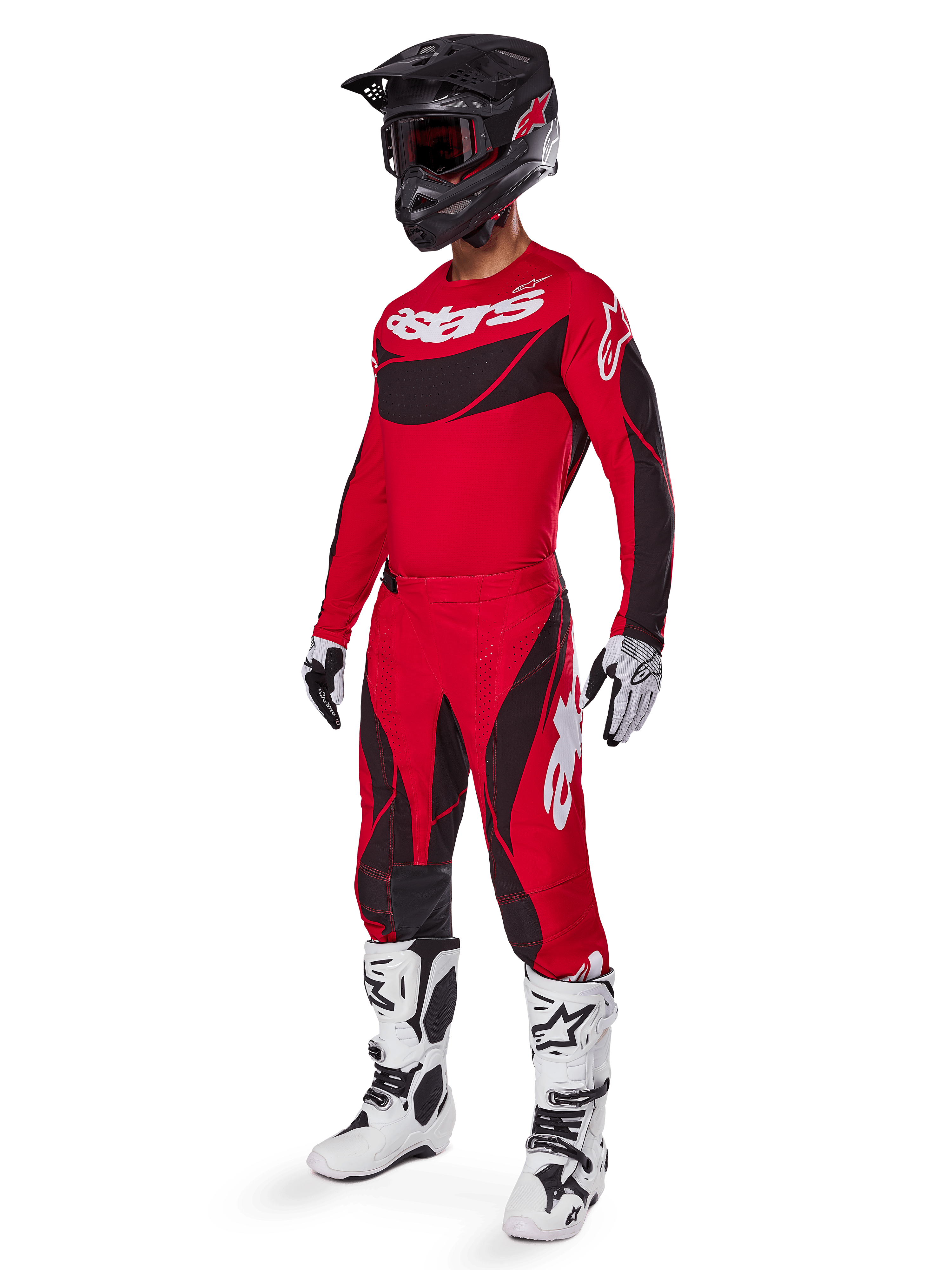 Motocross-kører iført komplet racerudstyr med Alpinestars 2025 Techstar Dreem bukser i klar rød og sort, matchende rød og sort trøje med hvidt logo, sort hjelm og hvide og sorte støvler, koordineret outfit til off-road racing
