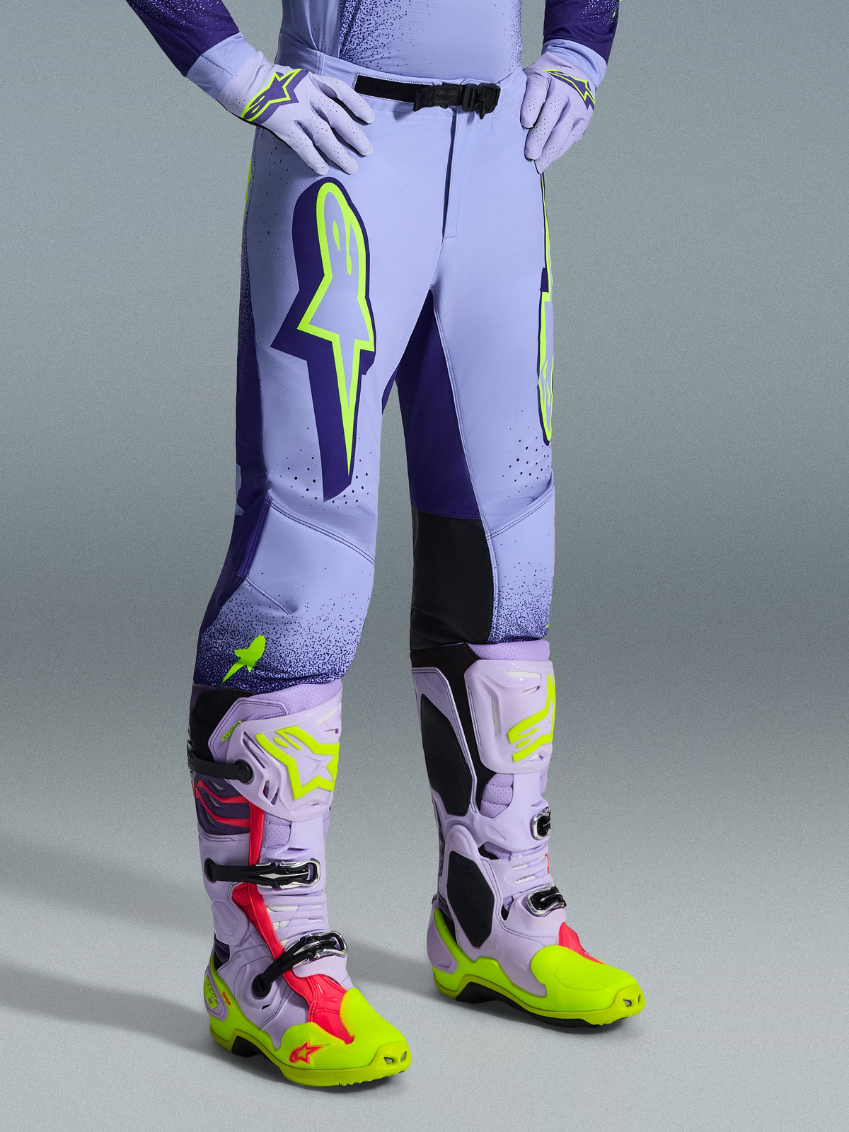 Alpinestars 2026 Supertech Scenz bukser, motocrossbukser, lilla og neongul, båret med matchende motocrossstøvler og handsker, med store neongule logoer, atletisk pasform og laserudskårne perforeringer til ventilation