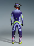 Motocrosskører set bagfra iført Alpinestars 2026 Supertech Scenz bukser i Purple Yellow Fluo, matchende trøje med lilla graduering og neongul grafik, sort hjelm og lilla støvler, koordineret professionelt racerudstyr til terrænkørsel