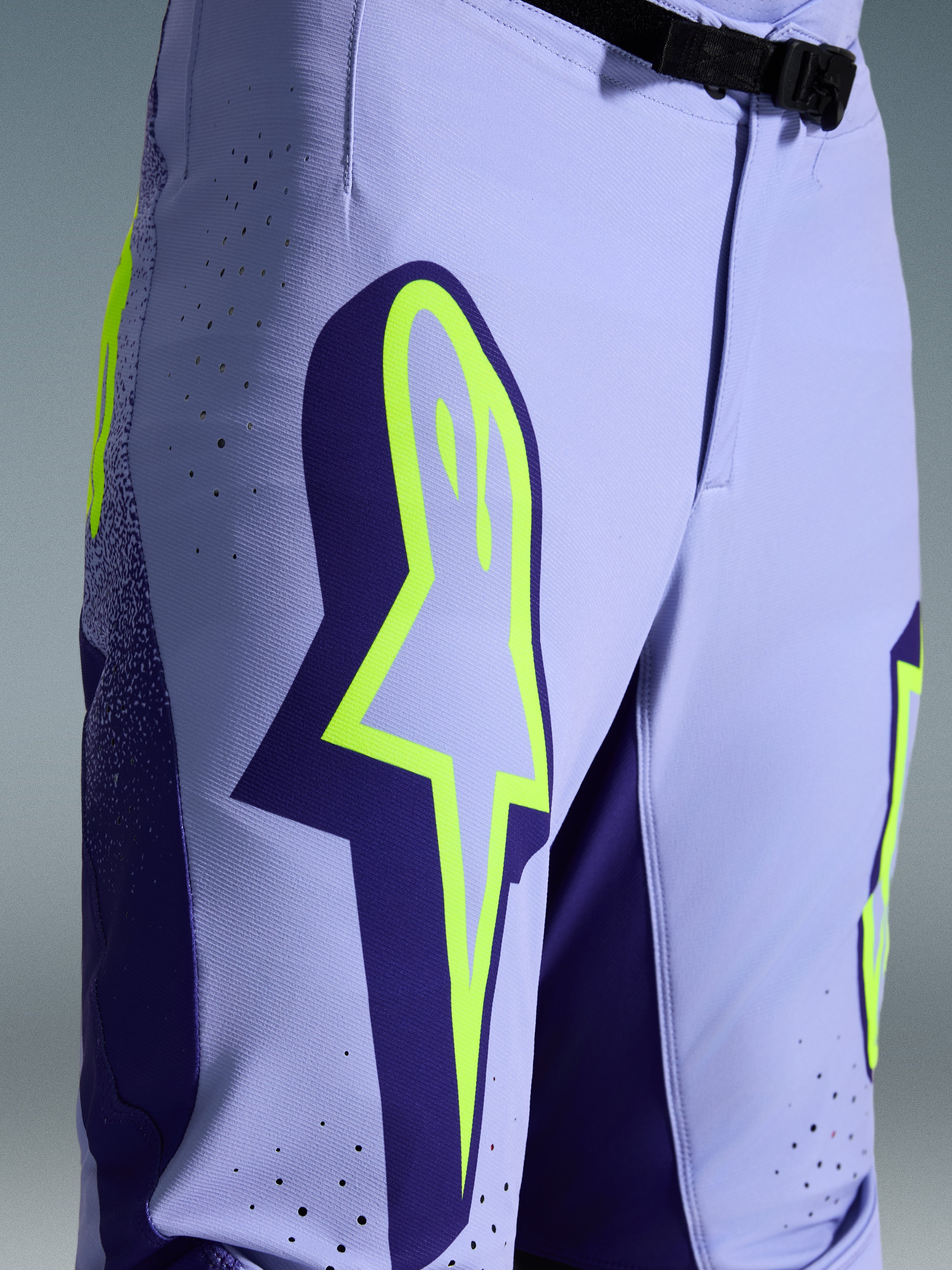 Alpinestars 2026 Supertech Scenz bukser, motocrossbukser, lilla og fluoriserende gul, nærbillede med stort gult logo på låret, laserskårne perforeringer til ventilation og magnetisk taljespænde, off-road udstyr med atletisk pasform