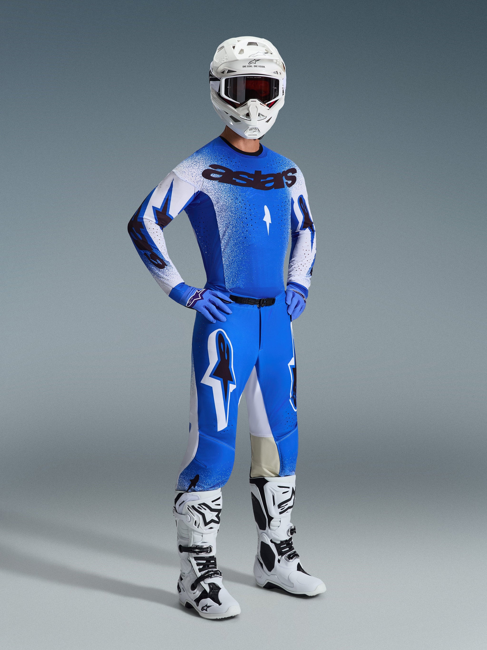 Motocross rider wearing complete racing gear, featuring the 2026 Supertech Scenz Pants in Ucla Blue and White, matching blue and white jersey with Astars logo, white helmet with red goggles, and white and black boots, coordinated outfit for professional off-road racing.