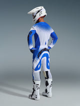Motocross rider from the rear wearing the 2026 Supertech Scenz Pants and jersey in Ucla Blue White, white helmet with Alpinestars logo, white and black motocross boots, professional off-road racing gear set.