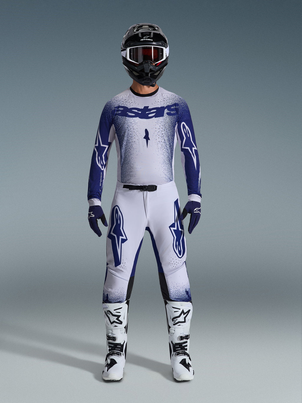 Alpinestars 2026 Supertech Scenz udstyrssæt, komplet motocross-udstyr i lysegrå og mørkeblå, inklusive trøje og bukser med matchende blå handsker, hvide og sorte støvler samt sort hjelm med hvide goggles, koordineret outfit til professionel terrænkørsel