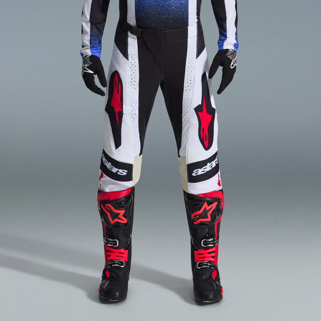 Alpinestars 2026 Techstar Knif-udstyrssæt, motocross-udstyr, sorte og hvide bukser med store røde stjernelogoer, båret med sorte og røde racingstøvler og sorte handsker, professionel atletisk pasform til off-road-performance