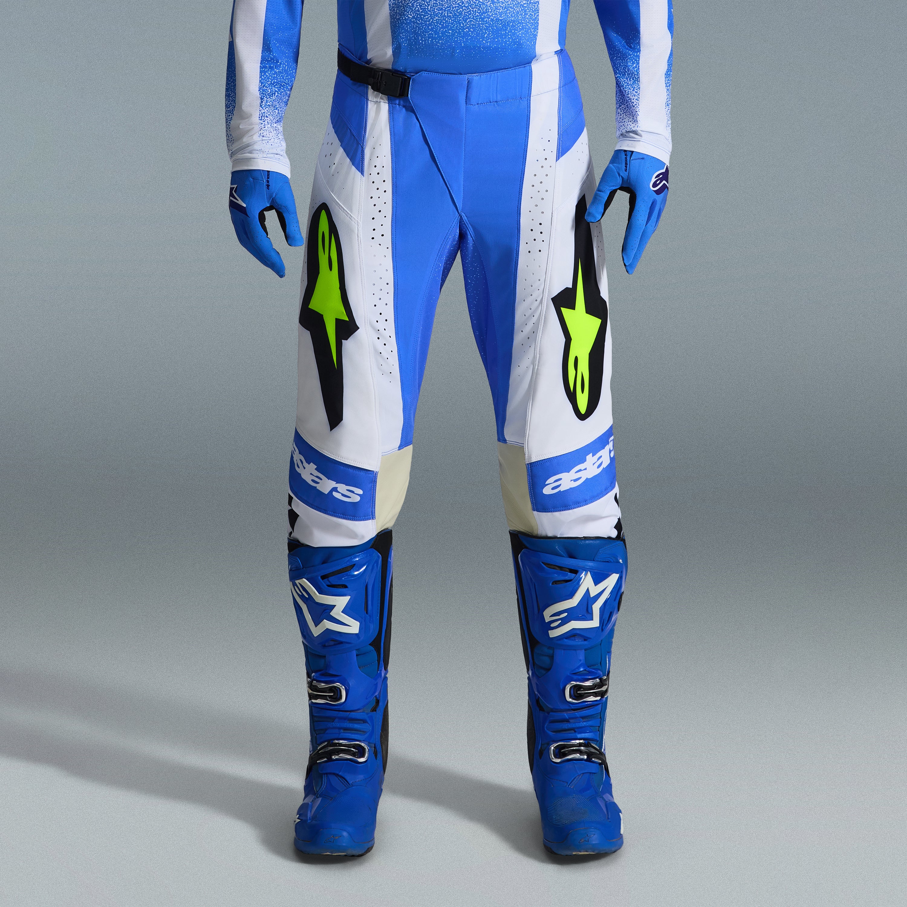 Alpinestars 2026 Techstar Knif udstyrssæt, blå og hvide motocrossbukser med fluorescerende gule logoer, matchende blå støvler og handsker, professionelt atletisk raceroutfit til terrænkørsel
