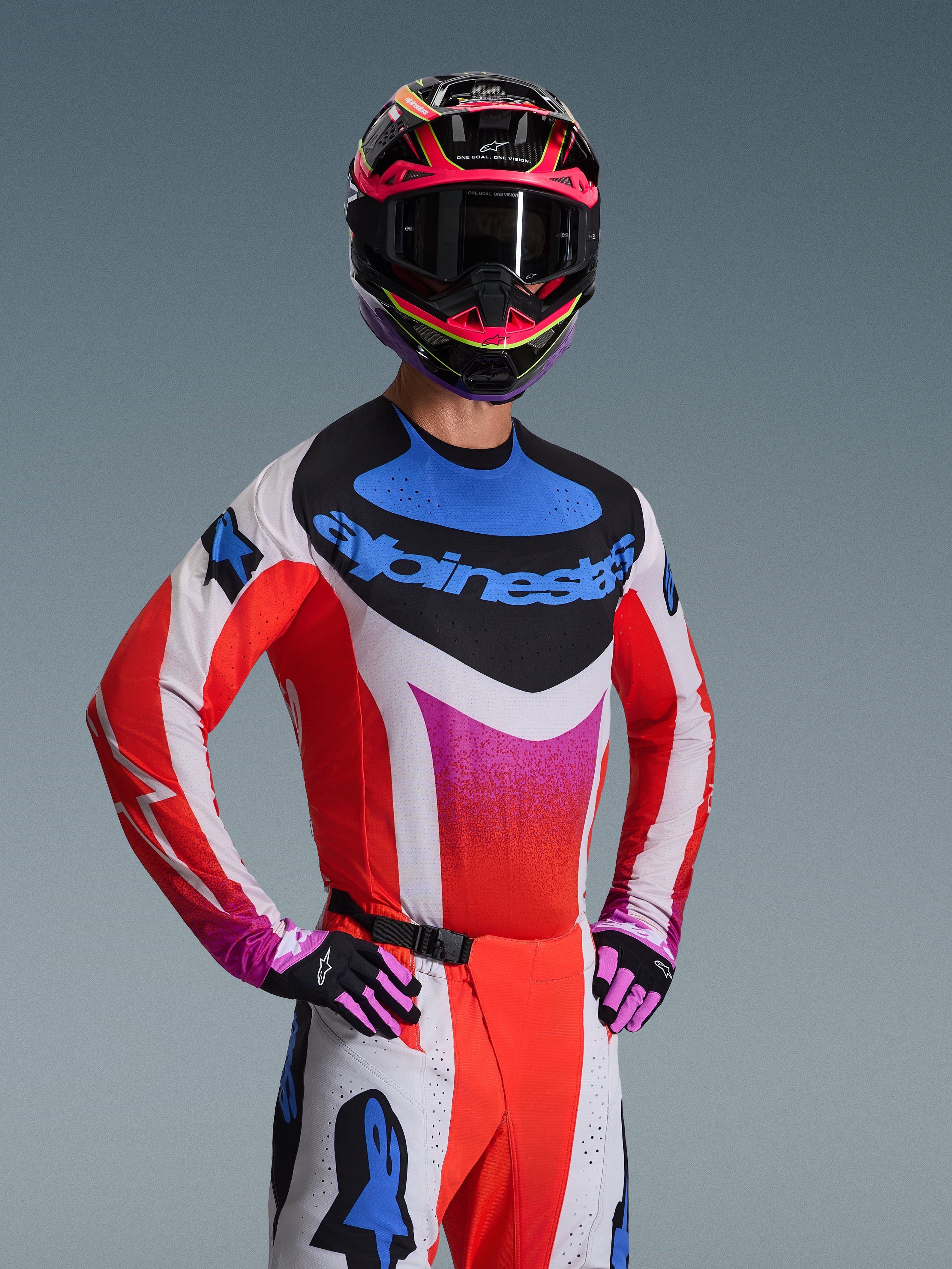 Alpinestars 2026 Techstar Knif Jersey, motocross-trøje, hvid med røde, blå og lyserøde gradientmønstre, med markant blåt logo på brystet, båret med matchende hjelm og handsker, atletisk racing-design til off-road kørsel