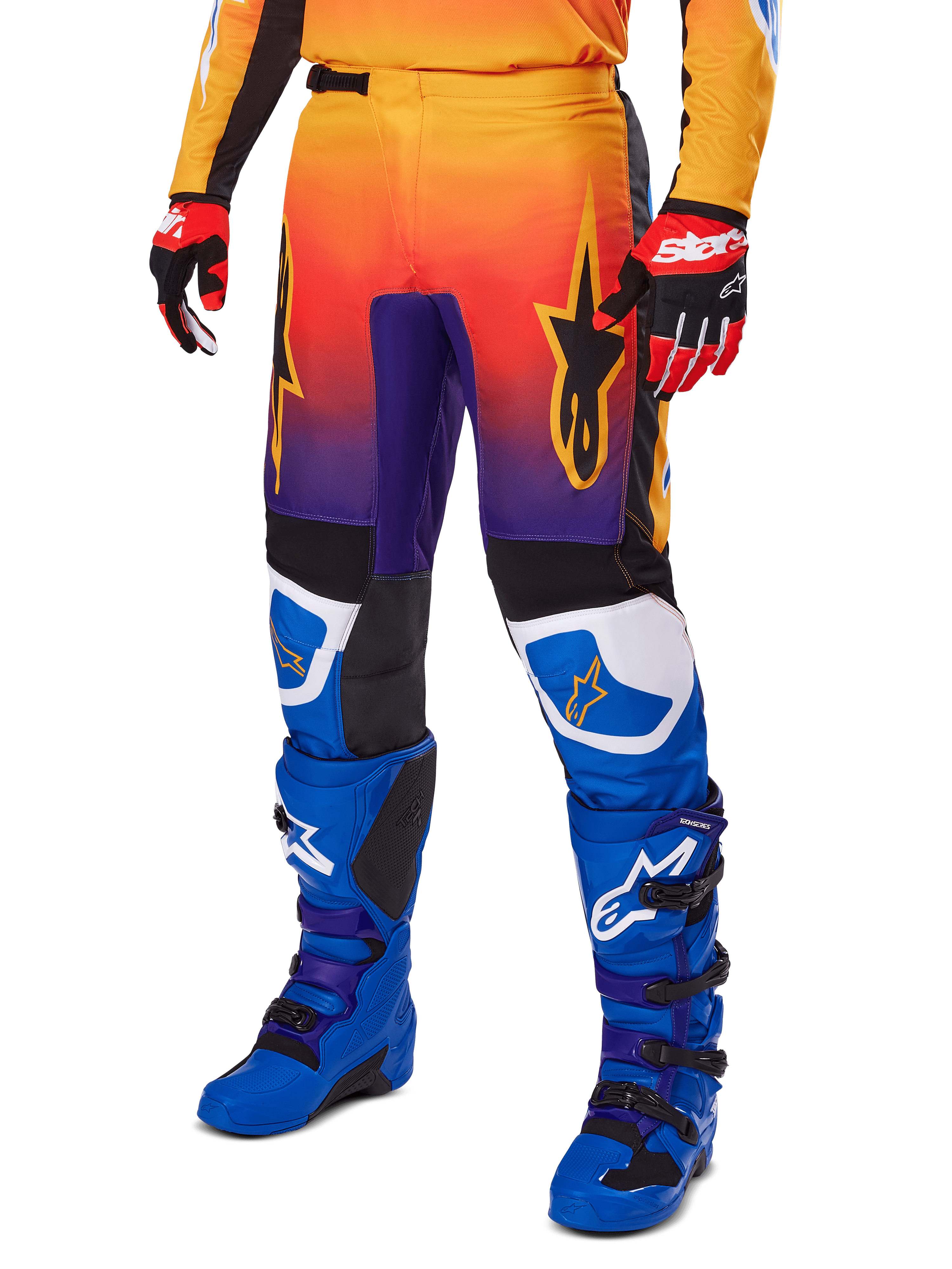 Alpinestars 2025 Fluid Wurx bukser, motocross-bukser, multifarvet orange, rød og lilla farveovergang med sorte og blå paneler, båret med blå støvler og røde handsker, med stjernelogo-grafik og hvide knædetaljer, slidstærkt performance-udstyr til off-road racing