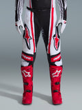 Alpinestars 2026 Techstar Nomur bukser, motocross-bukser, sort, hvid og rød, båret med matchende røde støvler og hvide handsker, med fremtrædende røde logoer på lårene og 'astars'-branding på knæene, multi-panel racingdesign til off-road ydeevne