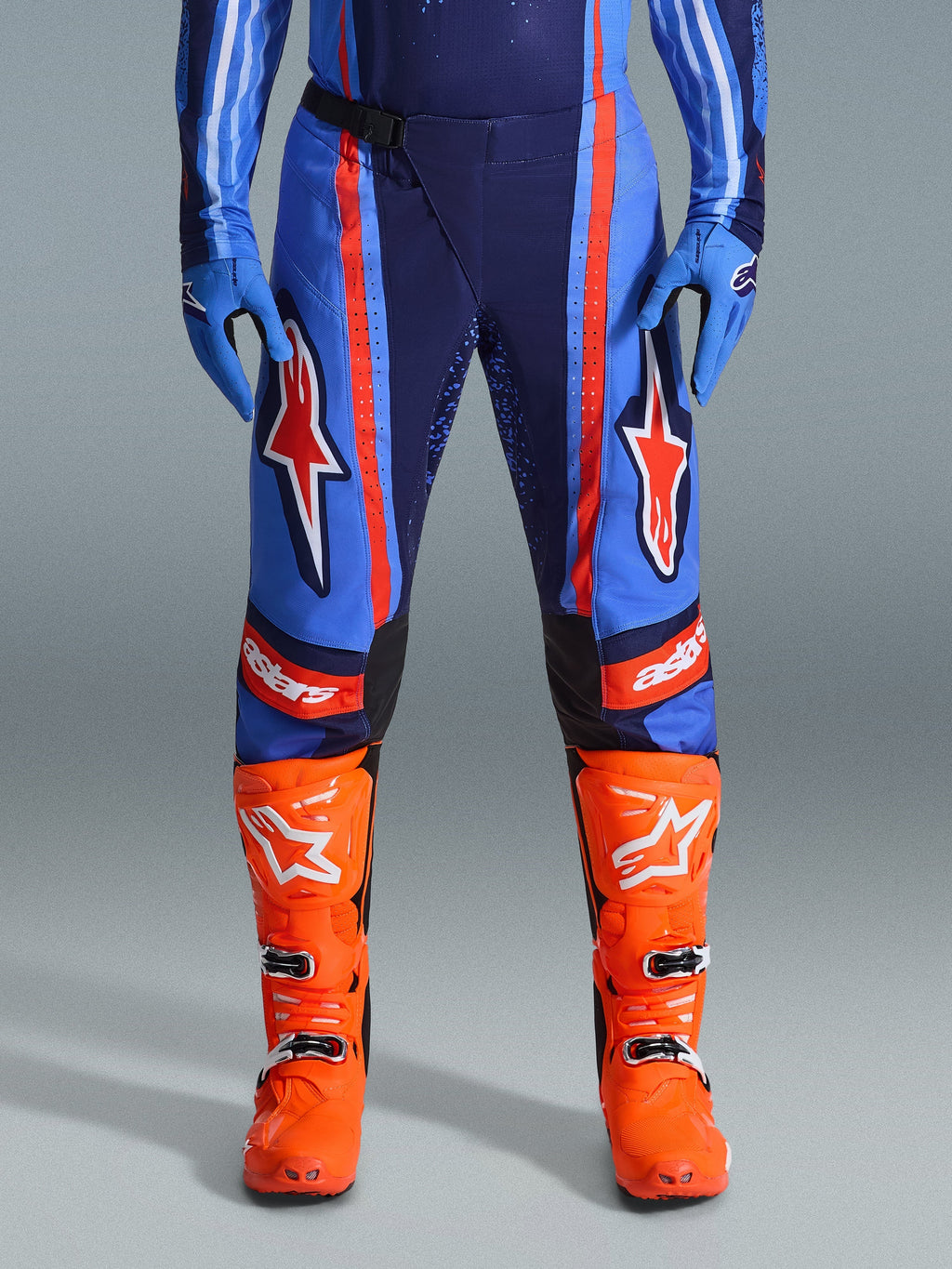 Alpinestars 2026 Techstar Nomur bukser, motocross-bukser, mørkeblå, orange og UCLA-blå, med markante orange striber og store hvide stjernelogoer på lårene, båret med stærke orange racingstøvler og blå handsker, atletisk race-pasform til off-road-ydeevne