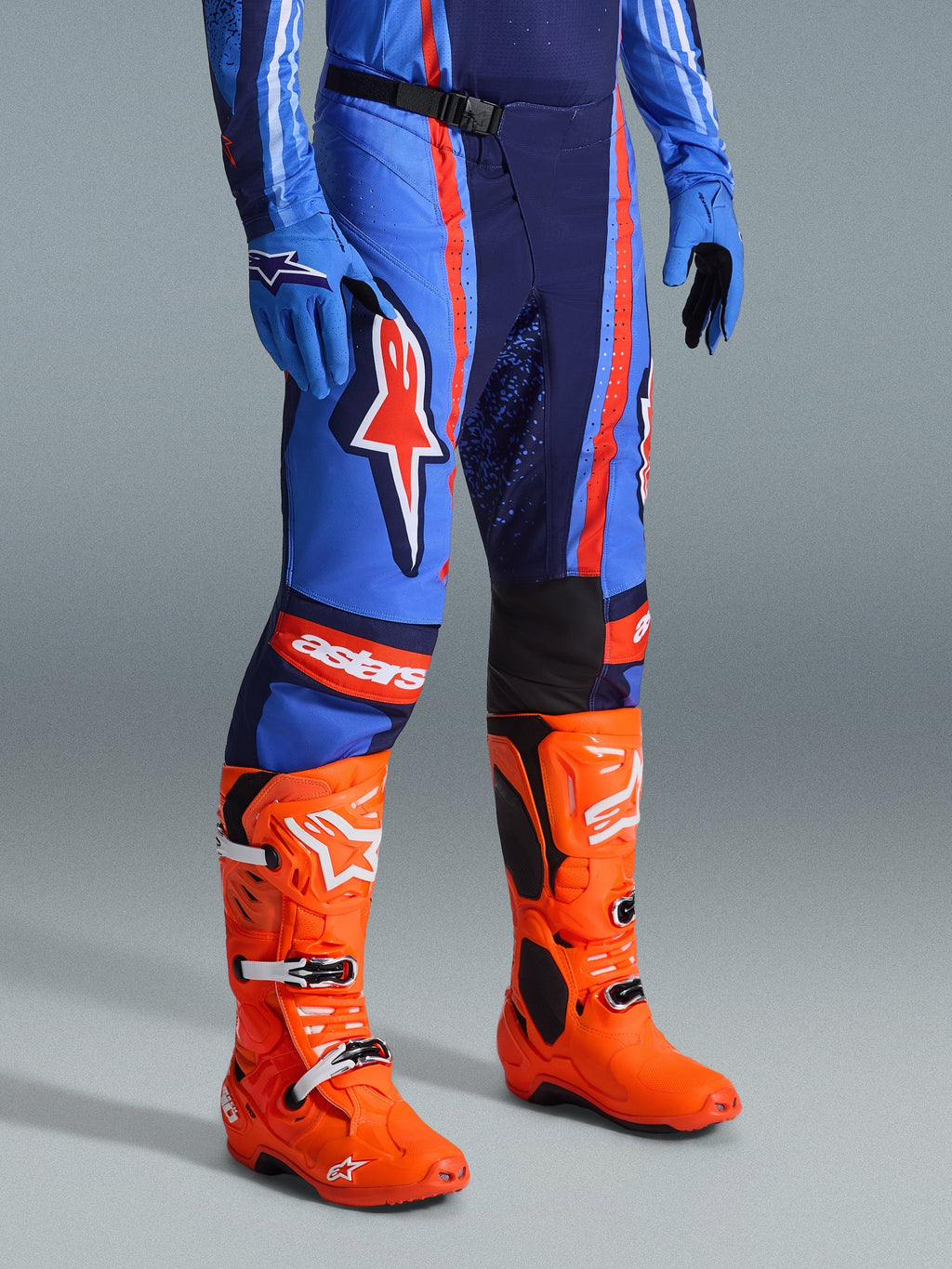 Alpinestars 2026 Techstar Nomur bukser, motocross-bukser, mørkeblå, orange og UCLA blå, båret med stærkt orange motocross-støvler og matchende blåt udstyr, med markant branding og multi-materiale konstruktion til off-road ydeevne.