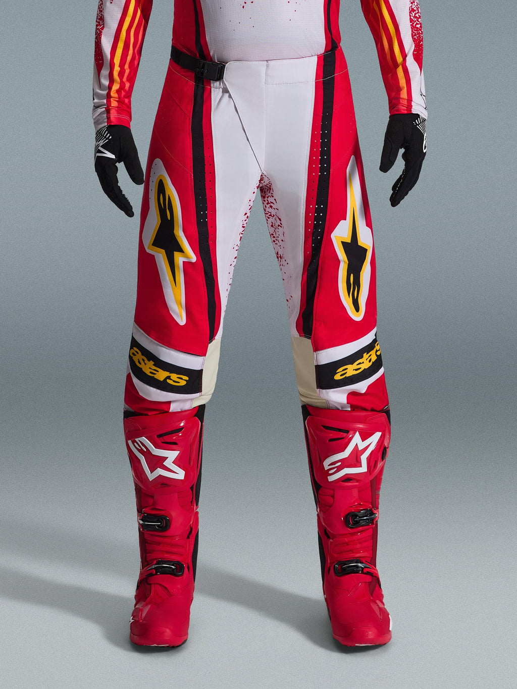 Alpinestars 2026 Techstar Nomur bukser, motocross-bukser, rød og hvid med sorte og gule detaljer, båret med matchende røde støvler og sorte handsker, performance-udstyr til terrænkørsel