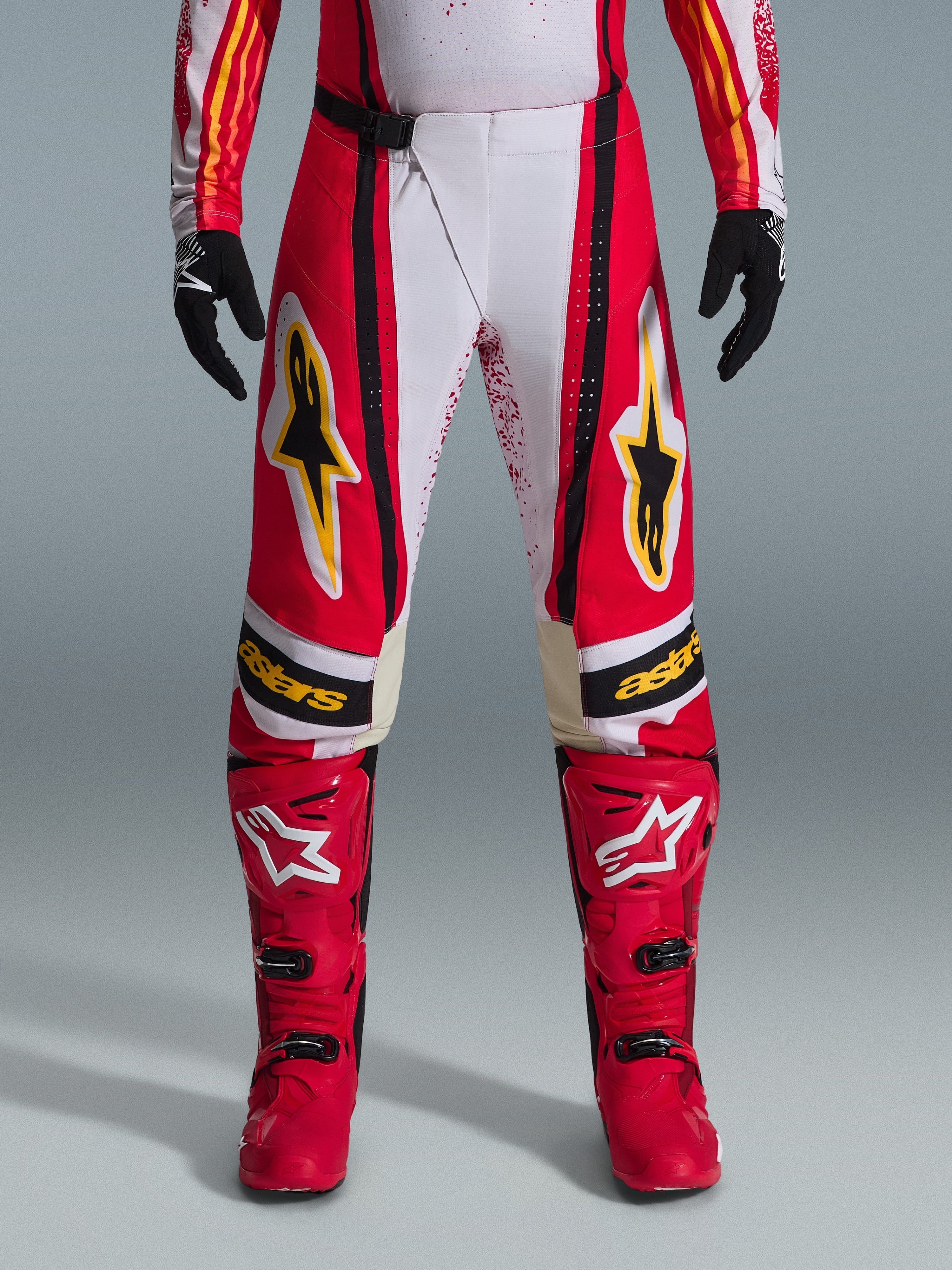 Alpinestars 2026 Techstar Nomur bukser, motocross-bukser, rød og hvid med sorte og gule detaljer, båret med matchende røde støvler og sorte handsker, performance-udstyr til terrænkørsel
