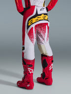 Alpinestars 2026 Techstar Nomur bukser, motocross-bukser set bagfra, rød og hvid med et markant gult logo bagpå, kombineret med knaldrøde Tech 10-motocrossstøvler, studieoptagelse på en grå baggrund