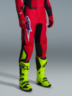 Alpinestars 2026 Fluid Grid bukser, motocross-bukser, rød, sort og lilla, båret med neongule støvler og røde handsker, med sorte paneler og et stort lilla og hvidt stjernelogo, holdbart sport-fit design til off-road racing