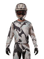 Alpinestars 2024 Racer Tactical trøje, motocross-trøje, Iron Camo Dust Gray kamuflage-mønster, kører iført matchende hjelm og beskyttelsesbriller med sorte handsker, teknisk udstyr til off-road racing