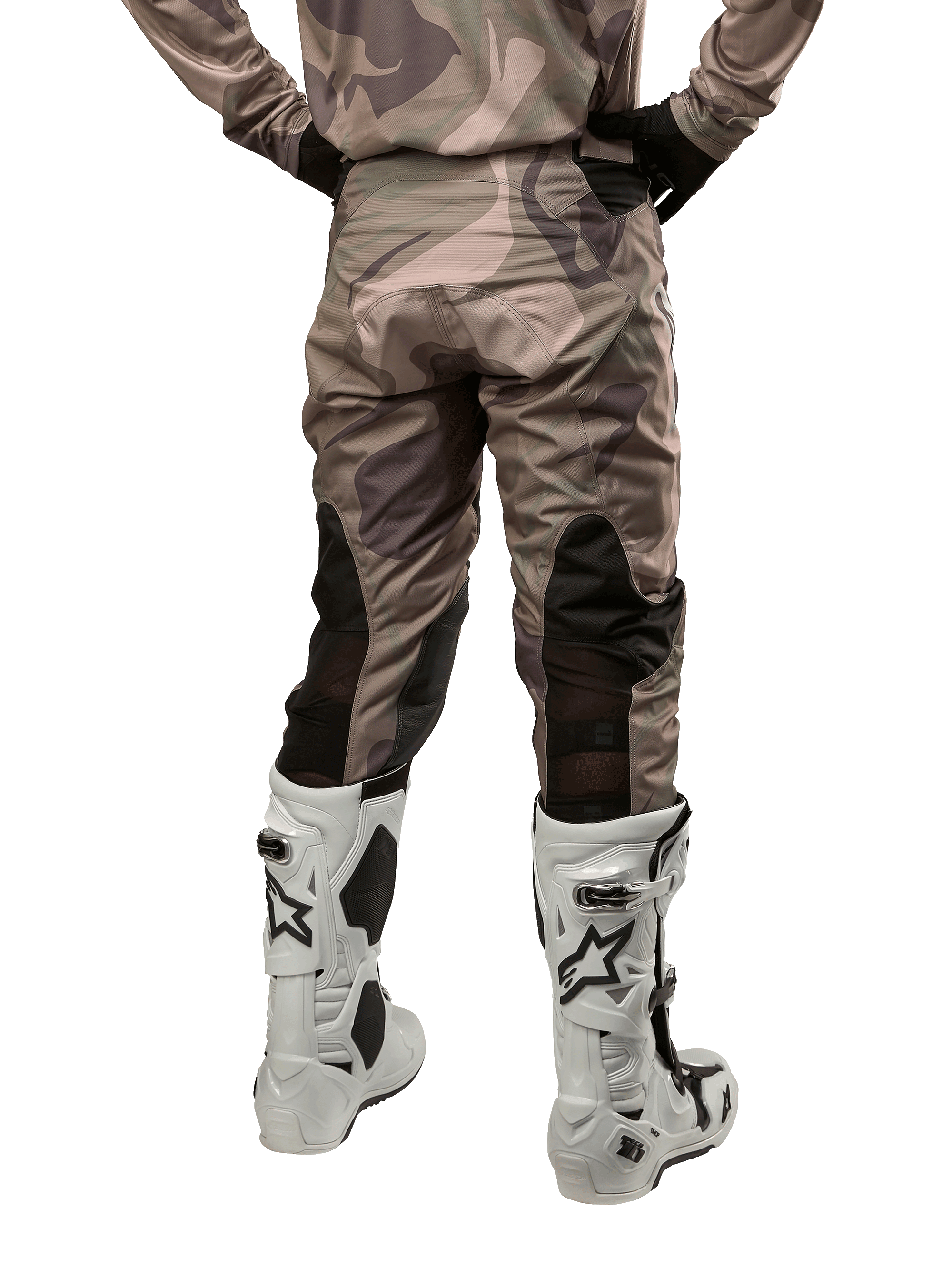 Alpinestars 2024 Racer Tactical bukser, motocrossbukser, Military Green Camo Brown, set bagfra med camouflagemønster og sorte åndbare strækpaneler på underbenene, båret med hvide motocrossstøvler, slidstærkt teknisk udstyr til off-road kørsel