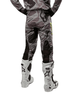 Alpinestars 2024 Racer Tactical bukser, motocross-bukser, Cast Gray Camo Magnet, set bagfra med camouflagemønster og sorte åndbare strækzoner, hvide og sorte motocross-støvler, designet til off-road kørsel