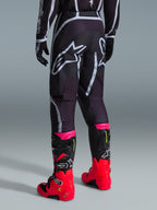 Alpinestars 2026 Fluid Apex bukser, motocrossbukser, sort og grå, set bagfra med store hvide Alpinestars-logoer på sædet, båret med stærkt røde og lyserøde støvler, holdbar 600D polystof-konstruktion til off-road kørsel