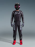 Alpinestars 2026 Fluid Apex-udstyrssæt, motocross-outfit, sort med grå detaljer, jersey med stort hvidt Astars-logo, matchende bukser med tydelig branding, sort hjelm med pink goggles og stærkt røde støvler, komplet off-road racerudstyr