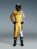 Alpinestars 2026 Fluid Apex bukser, motocrossbukser i gul, sort og hvid, båret som et komplet racersæt med matchende gradient-jersey, sort hjelm og støvler, professionelt off-road køreudstyr