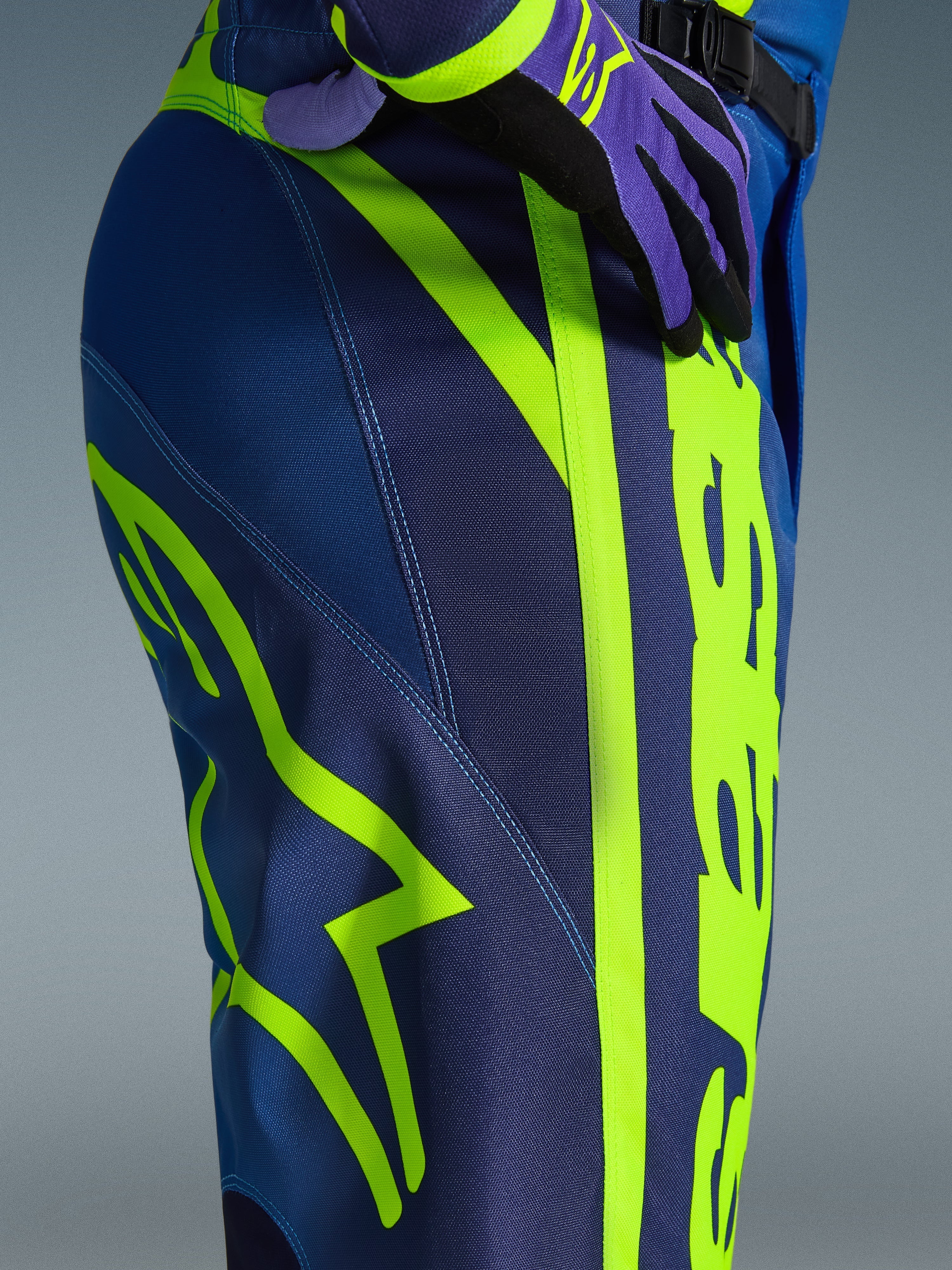 Alpinestars 2026 Fluid Apex bukser, motocrossbukser, blå og neongul, nærbillede af siden og hoften med markant neongult Alpinestars-logo, holdbart polystof-materiale til off-road kørsel, del af matchende udstyrssæt