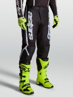Alpinestars Fluid Apex V2 bukser, herre MX bukser, sort og sølv, slidstærk 600D polyfabric, vist med gule støvler