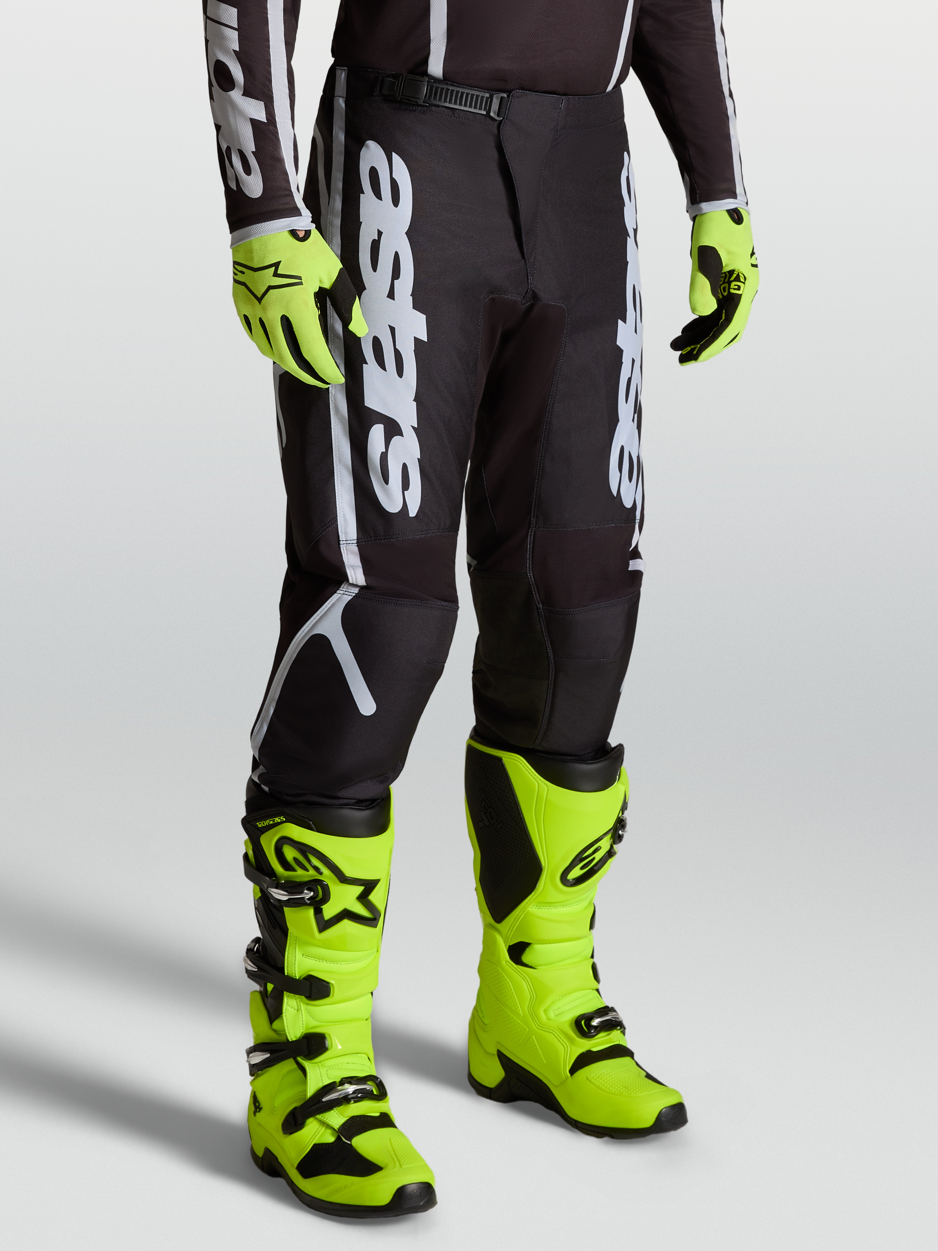 Alpinestars Fluid Apex V2 bukser, herre MX bukser, sort og sølv, slidstærk 600D polyfabric, vist med gule støvler