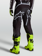 Alpinestars Fluid Apex V2 Bukser, motocrossbukser til mænd i sort og sølv, båret med gule støvler, bagfra