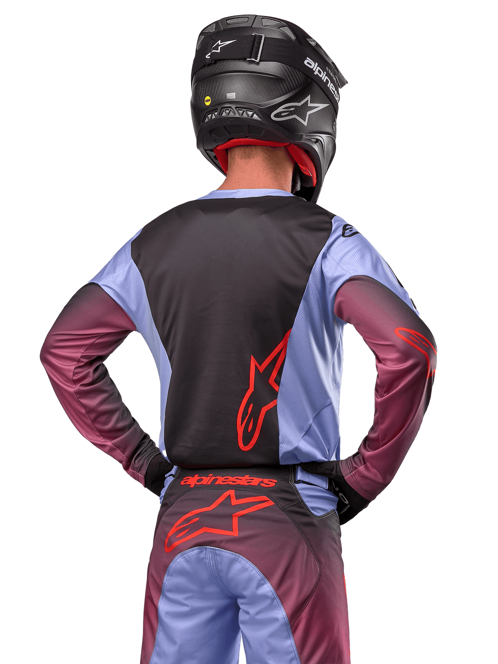 Alpinestars 2024 Racer Hoen-udstyr, motocrosskører set bagfra, Lavan Purple og sort jersey med rødt logo, matchende bukser med røde detaljer, sort hjelm, koordineret sæt til off-road racing