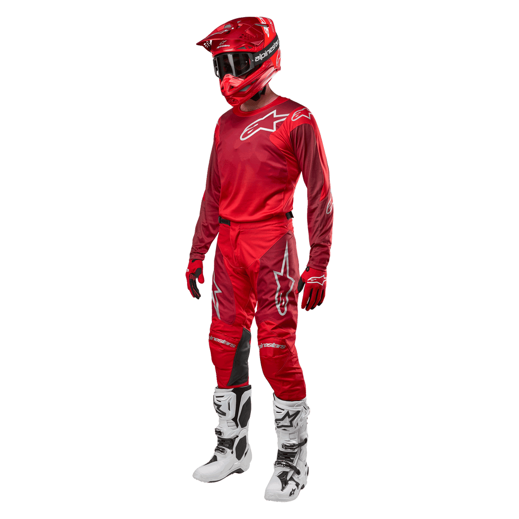 Motocross-kører iført komplet racerudstyr, Alpinestars 2024 Racer Hoen bukser og trøje i Mars Red Burgundy, rød hjelm, røde handsker og hvide og sorte støvler, koordineret outfit til terrænkørsel
