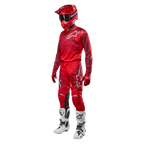 Motocross-kører iført komplet racerudstyr, Alpinestars 2024 Racer Hoen bukser og trøje i Mars Red Burgundy, rød hjelm, røde handsker og hvide og sorte støvler, koordineret outfit til terrænkørsel