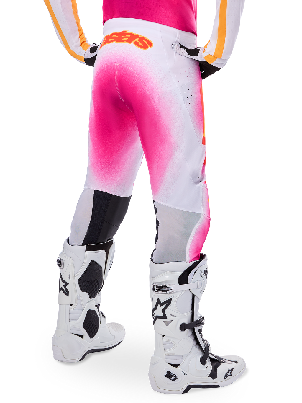 Alpinestars Supertech AFD MIG Limited Edition motocrossbukser, pink og hvid, set bagfra med en levende pink gradient-sprayeffekt, orange logo på taljen bagpå, kombineret med hvide og sorte Tech 10-støvler, professionelt terrænkørselsudstyr