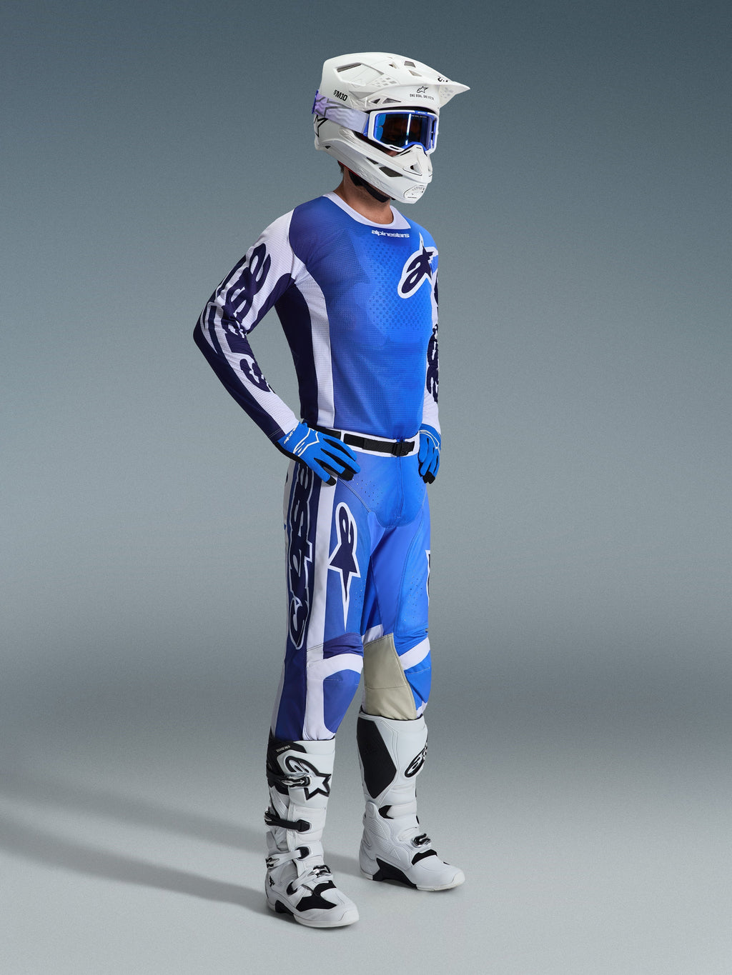 Motocross-kører iført 2026 Racer Air Portl-bukser i Ucla Blue White, kombineret med en matchende blå og hvid trøje, hvid hjelm med blå briller og hvide støvler, komplet udstyrssæt til off-road racing.