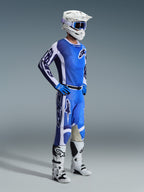 Motocross-kører iført 2026 Racer Air Portl-bukser i Ucla Blue White, kombineret med en matchende blå og hvid trøje, hvid hjelm med blå briller og hvide støvler, komplet udstyrssæt til off-road racing.