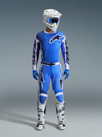 Alpinestars 2026 Racer Air Portl bukser, motocross-bukser, Ucla-blå og hvid, båret som en del af et komplet racersæt med en matchende trøje, hvid hjelm, blå goggles og hvide støvler, med perforerede paneler for høj luftgennemstrømning og markant branding til off-road ydeevne