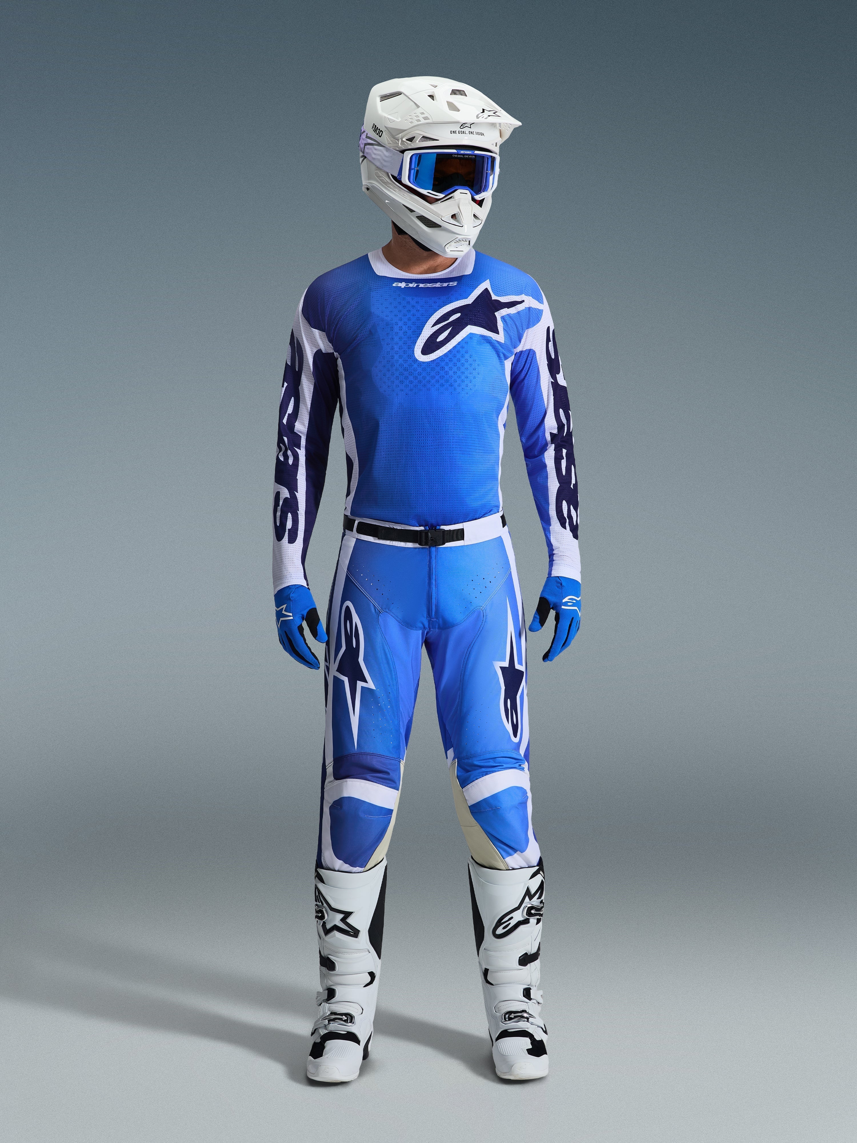 Alpinestars 2026 Racer Air Portl bukser, motocross-bukser, Ucla-blå og hvid, båret som en del af et komplet racersæt med en matchende trøje, hvid hjelm, blå goggles og hvide støvler, med perforerede paneler for høj luftgennemstrømning og markant branding til off-road ydeevne